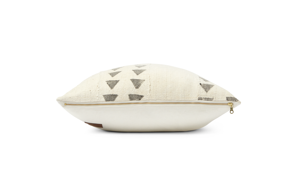 This is a full side view of the Clayson Mud cloth pillow.  It is off white with gray triangles on each side of the pillow and the exposed YKK exposed brass zipper.  The hemp cotton suede back is shown as well.